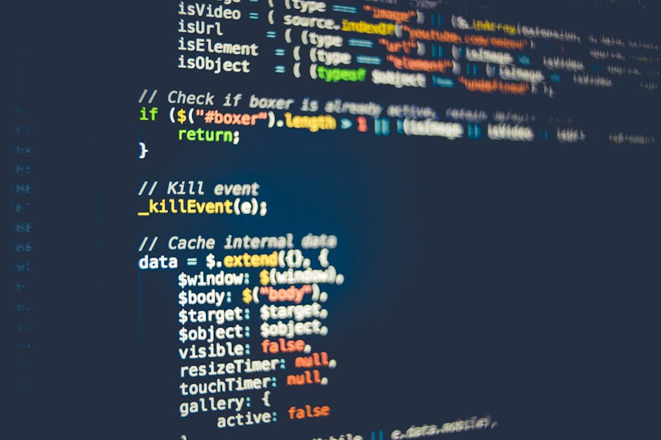 The image displays a close-up view of a computer screen with lines of color-coded programming code on a dark background, including syntax highlighting with green, yellow, white, red, and blue elements