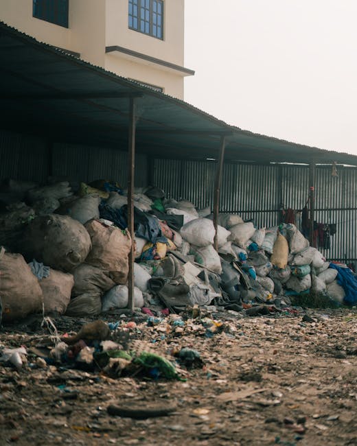An expansive pile of mixed household and commercial waste spread across an outdoor area, primarily composed of various types of plastic, paper, and cardboard materials. The plastic waste includes crum